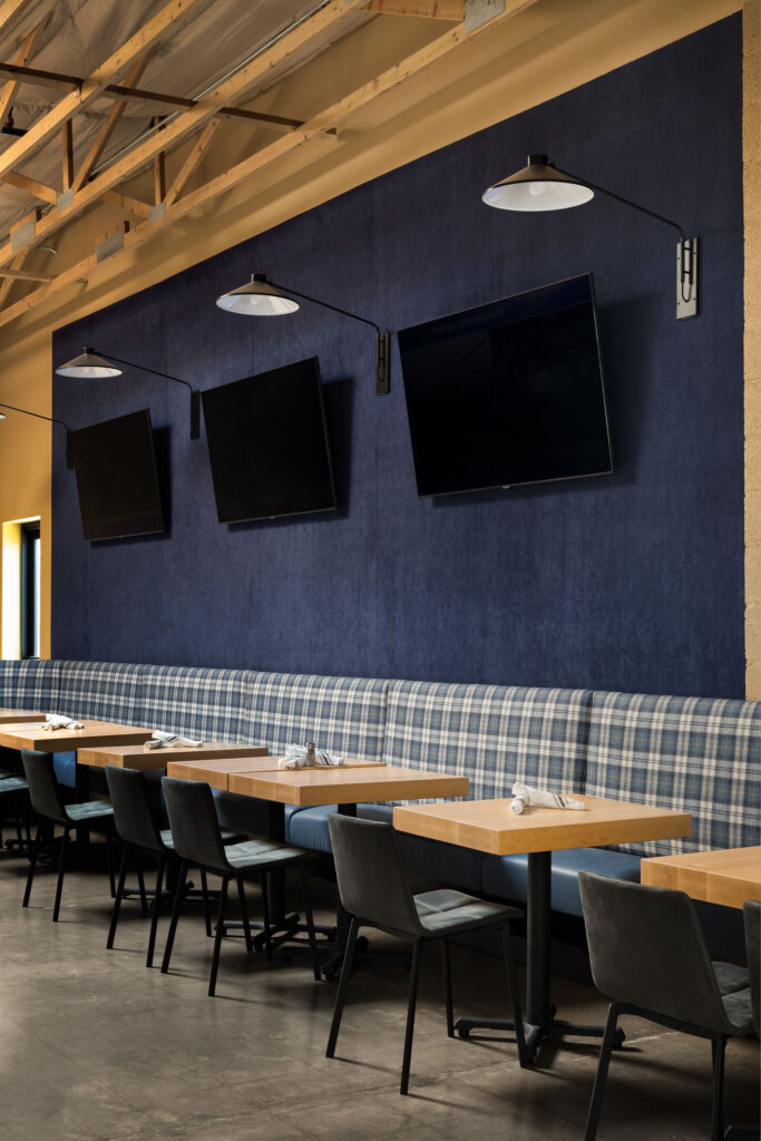 Cozy dining corner featuring navy walls, TVs, and plaid banquette seating.
